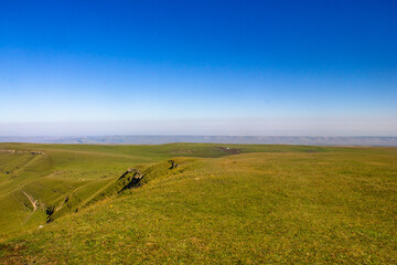 Beautiful alpine meadow on a sunny day with a gorge. Blue sky