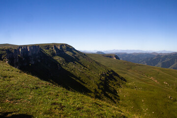 Fototapeta na wymiar Beautiful alpine meadow on a sunny day with a gorge. Blue sky