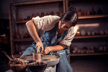 Stylish professional potter working on potter's wheel with raw clay with hands. National craft.