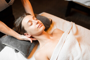 Obraz na płótnie Canvas Young woman receiving a facial massage, relaxing at Spa salon