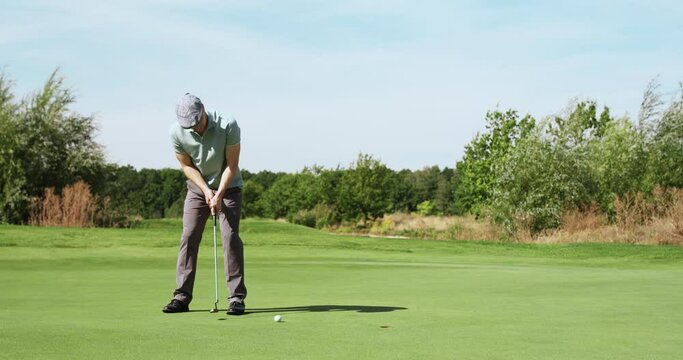 Perfect golf putt. Male golfer hitting ball and enjoying goal, playing outdoor at green course