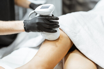 Young woman during an ultrasound liposuction procedure at luxury Spa salon. Doctor working on thigh...