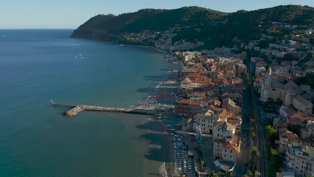drone flying backwards from the city of Laigueglia, Liguria during sunset