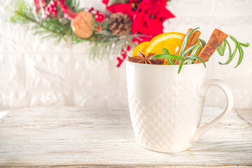 Traditional Winter Hot Alcohol Drink. Mulled Wine in a white Cup on the background of the kitchen table with Christmas decorations. 