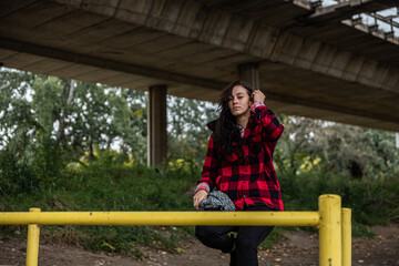 Young depressed homeless girl or woman sitting alone under the bridge on the street on the cold weather feeling anxious abandoned and freezing 