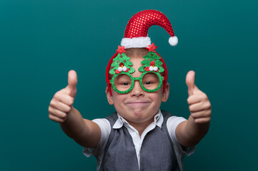 Portrait of happy cheerful boy wearing headband with Santa Claus Hat and funny glasses with Christmas trees