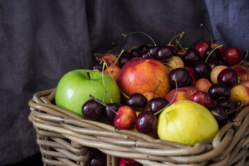 Summer fruits in basket on wooden table. Vibrant colors of beautiful cherries, apples  and nectarines. Healthy eating concept. Fresh fruits close up photo. 