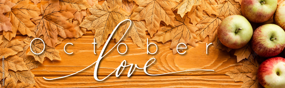 Wall mural top view of ripe apples and autumnal foliage near october love lettering on wooden background, panoramic shot