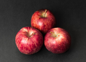 Three whole fresh apple fruit isolated on black texture background