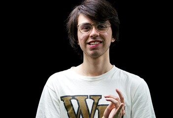 Young man smiling at the camera while messing with his hand
