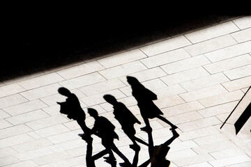 Abstract background shadow silhouette of four people walking city pavement - 390179061