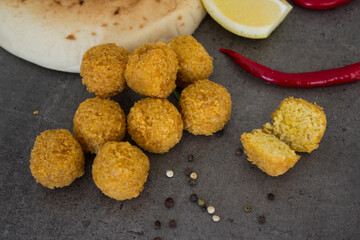 Fresh made falafels on dark grey table with lemon slices, chili pepper and parsley. Authentic food of Israel. Ingredients top view photo. Healthy eating concept. 