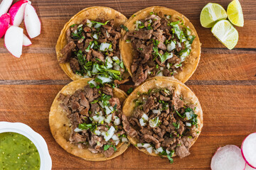 Flat lay of appetizing tacos, lemon, sauce, and radish on the table