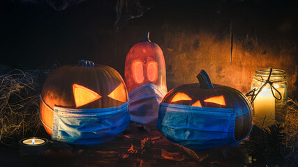 Halloween themed background, spooky pumpkins wearing face masks and candles in a dark setting