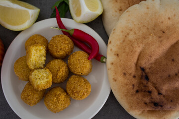Falafel - authentic food of Israel. Fresh ingredients top view: plate of falafels, pita bread, parsley, lemon, parsley and red pepper.  Wooden table background. Healthy food photo. 
