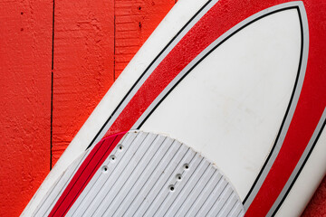 Surf rouge et blanc apposé sur une façade en planche de bois peinte en rouge