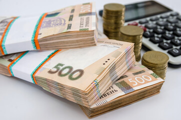 bundles of Ukrainian hryvnia, coins and calculator on a white background. The inscription on the packs 