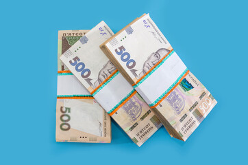 three bundles of hryvnia on a blue background. A stack with 500 hryvnia. Much money. Close-up.