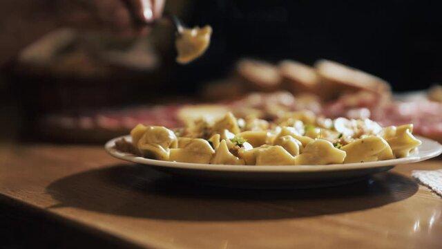 Close Up of Fork Picking Up Fresh Piece of Tortellini Pasta from Plate