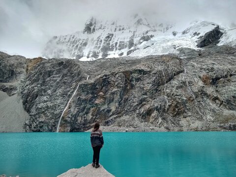 Girl at Laguna Paron, Huaraz, Peru. A blue-green lake in the Cordillera Blanca on the Peruvian Andes. At 4185 meters above sea level, it's surrounded by snowy peaks and a pyramid mountain. 