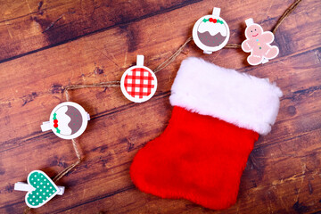 Obraz na płótnie Canvas Christmas flat lay of a small empty stocking and seasonal decorative clip on shapes on a rustic wood background
