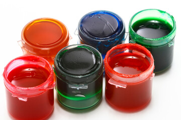 Pots of colourful acrylic glass paints isolated on a white background