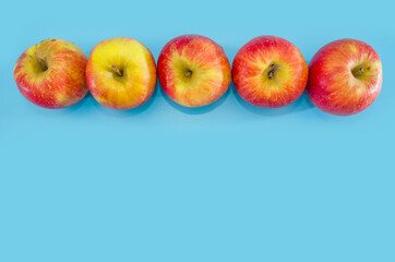 row of red apples on a blue background. view from above. copy space.