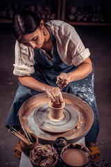 Stylish artisan master posing while making earthenware. Handicraft production.