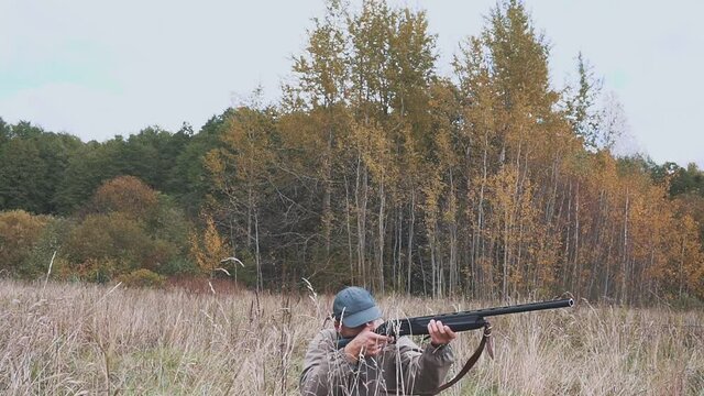 A man with a shotgun in his hands on a hunt in the field and forest