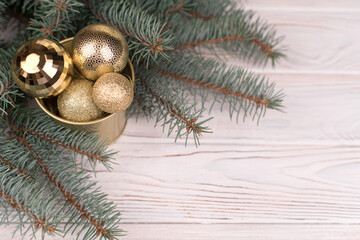 Stylish bucket of Christmas Golden toys on a white wooden background and branches of Christmas trees