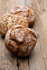 Gold rustic crusty loaves of bread and buns on wooden background. Still life captured from above top view, flat lay.