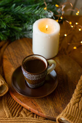 a cup of coffee and a candle on a chalkboard on a cozy warm sweater and a sprig of a Christmas tree