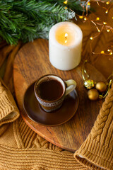 a cup of coffee and a candle on a chalkboard on a cozy warm sweater and a sprig of a Christmas tree