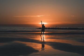 Woman on the beach making the peace gesture during sunset