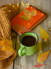 mug of hot chocolate on a wooden table, still life with a book and yellow leaves and garlands
