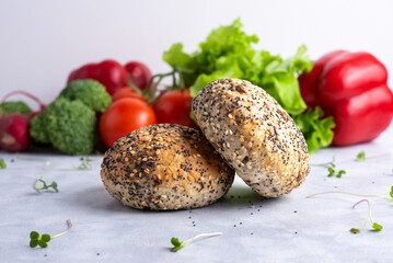 Two cereal buns on a white plate with red and green vegetables