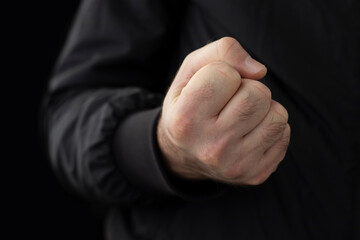 Male fist close-up on black background.