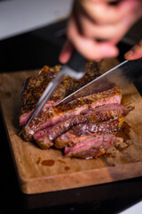 Sliced grilled meat steak Rib eye on meat fork and Pepper sauce on dark background