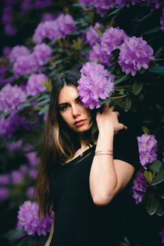 Portrait of woman standing by rhododendron tree