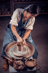 Beautiful professional potter is working on pottery wheel. Hand work.