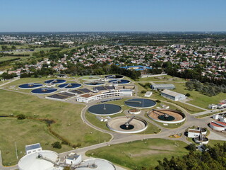 Vista aérea de una planta dedicada al tratamiento de efluentes de agua y la ciudad al fondo