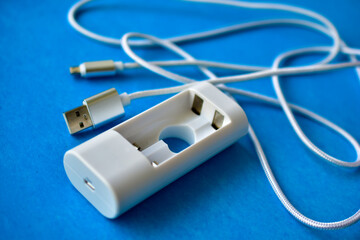 White USB cable and battery charger on a blue background