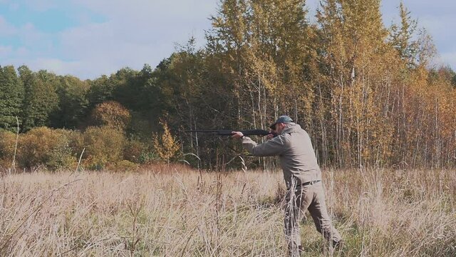 A hunter with a gun tracks down the prey. Aim a hunting rifle. Beautiful autumn forest.