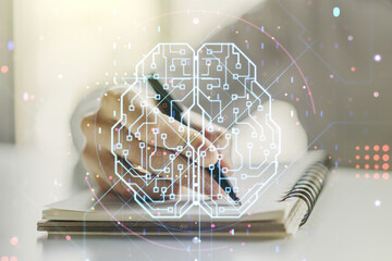 Creative artificial Intelligence concept with human brain hologram and man hand writing in notebook...