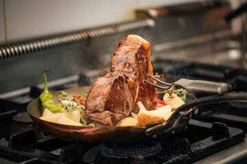 Delicious t-bone steak with vegetables cooking in pan.
