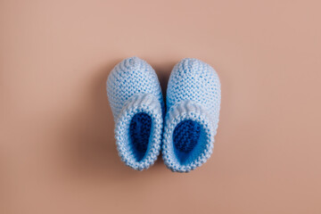 Cute newborn baby boy shoes with over beige background. Baby shower, birthday, invitation or greeting card idea
