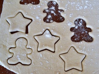 Christmas cookie dough stretched and cut with molds in the shape of a gingerbread man, stars and trees