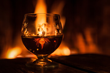 glass with alcohol standing against the background of fire in the fireplace