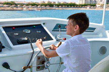 Obraz premium Teen at the helm controls a yacht at sea