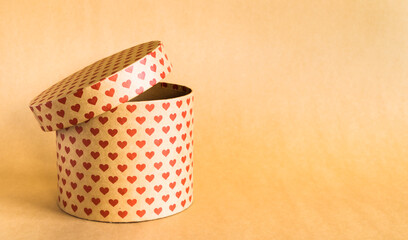 Valentine's Day concept. Paper round gift box with hearts print on natural background. 